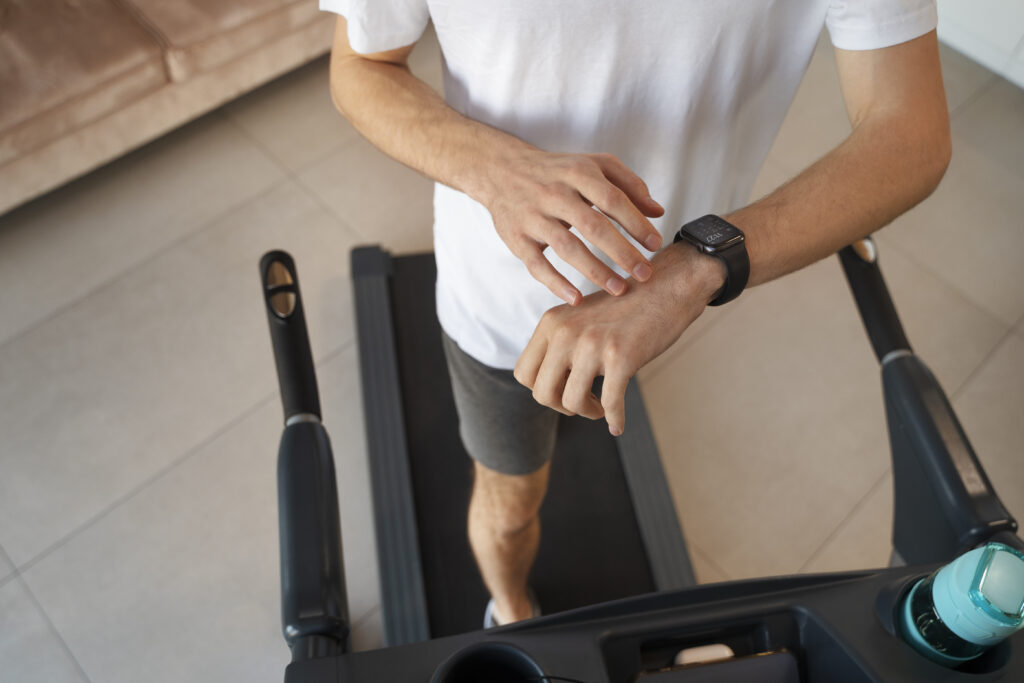 Homem andando na esteira e observando seu smartwatch